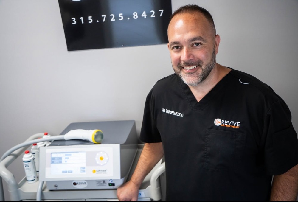 Dr. Tim DelMedico, DC beside a SoftWave TRT unit in his clinic