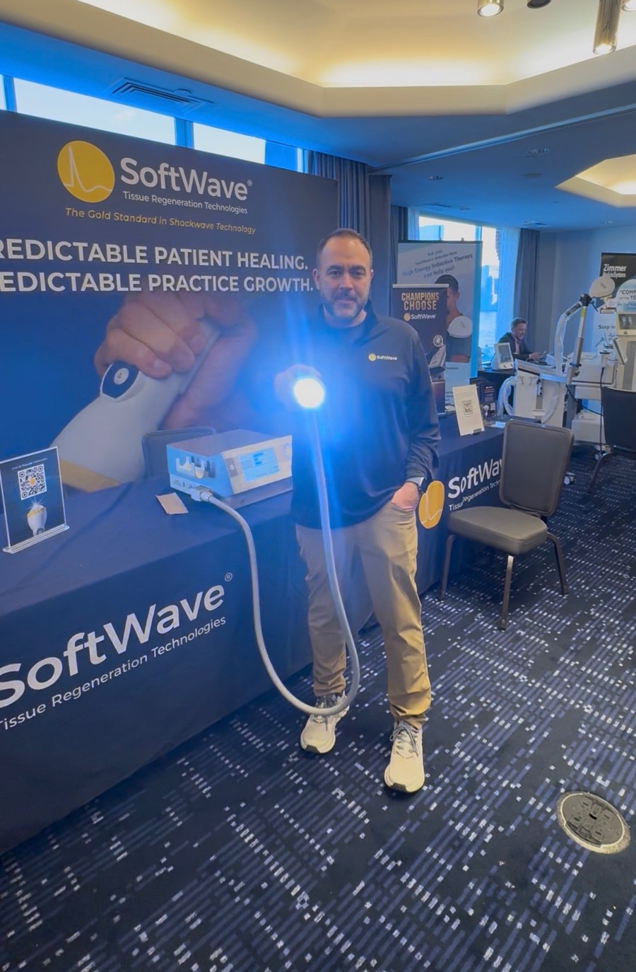 Dr. Tim DelMedico at the SoftWave TRT booth holding an active applicator
